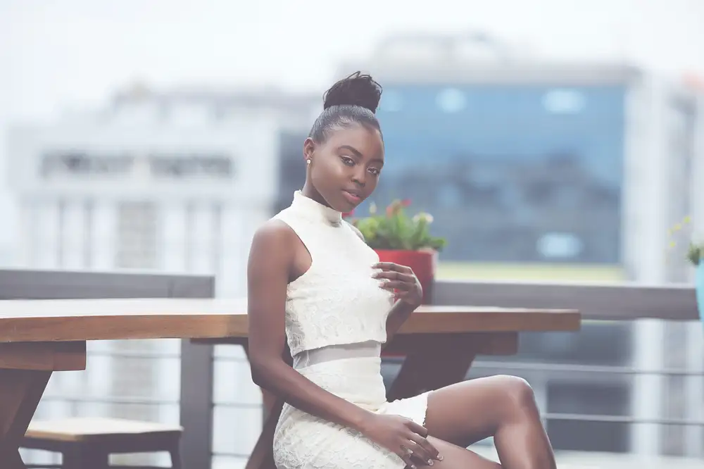 Lady on a rooftop wearing a white two piece cloth with her legs crossed