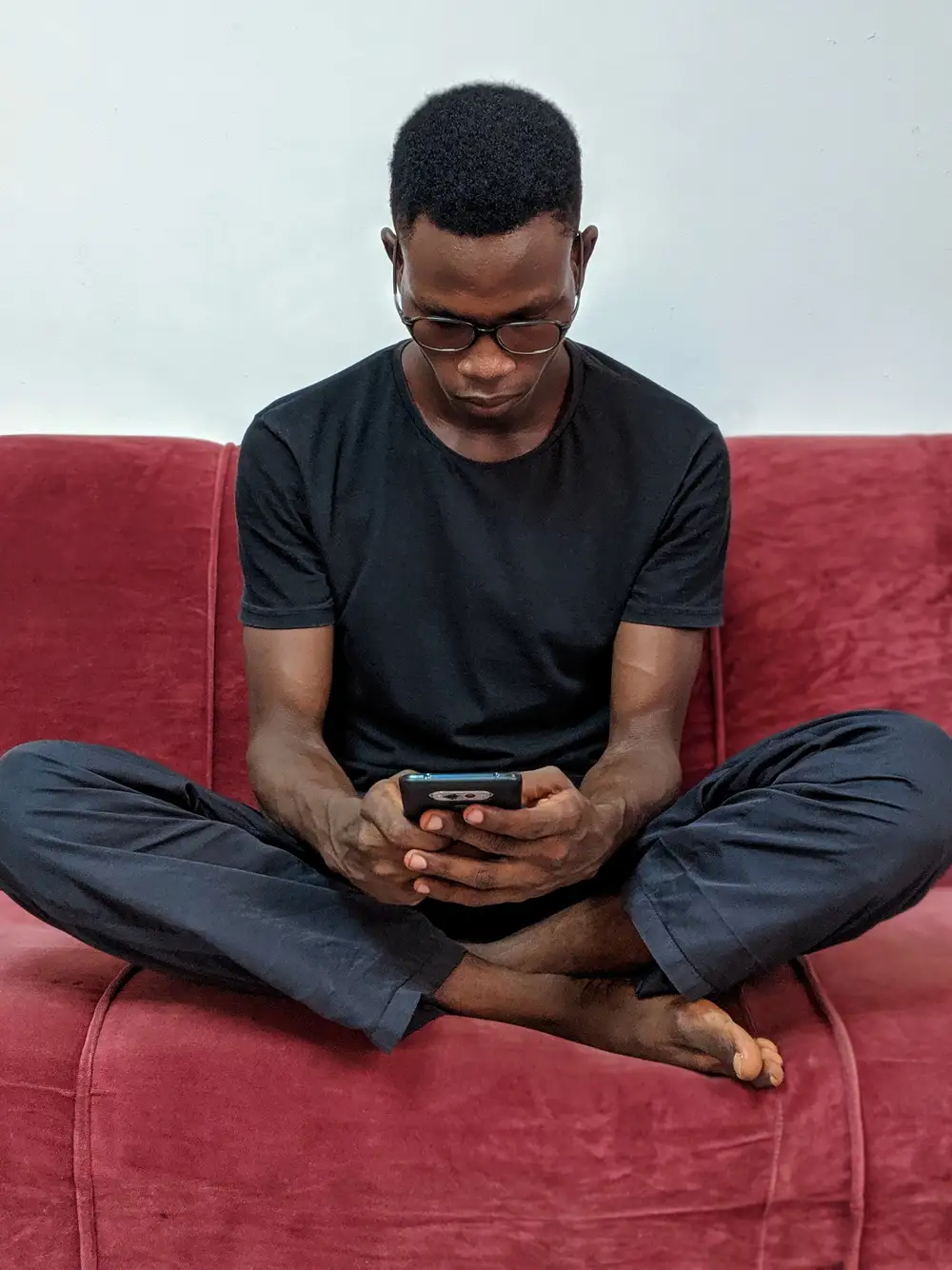 man sitting on couch while holding a phone