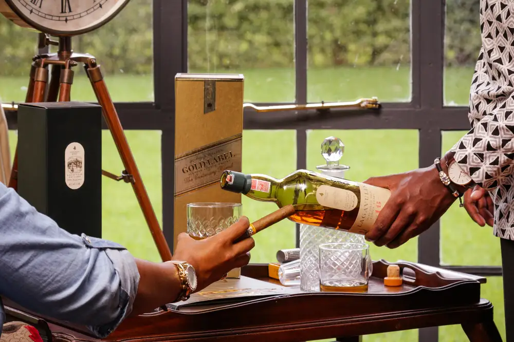 Man serving whiskey to a man holding cigar