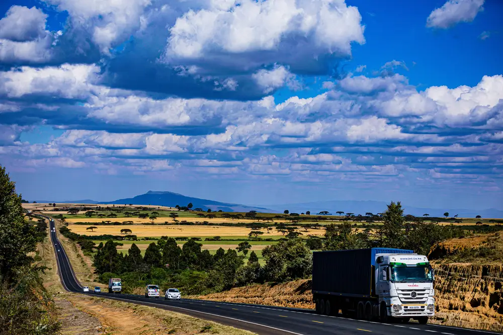 Vehicles moving on a long highway under the summer sky