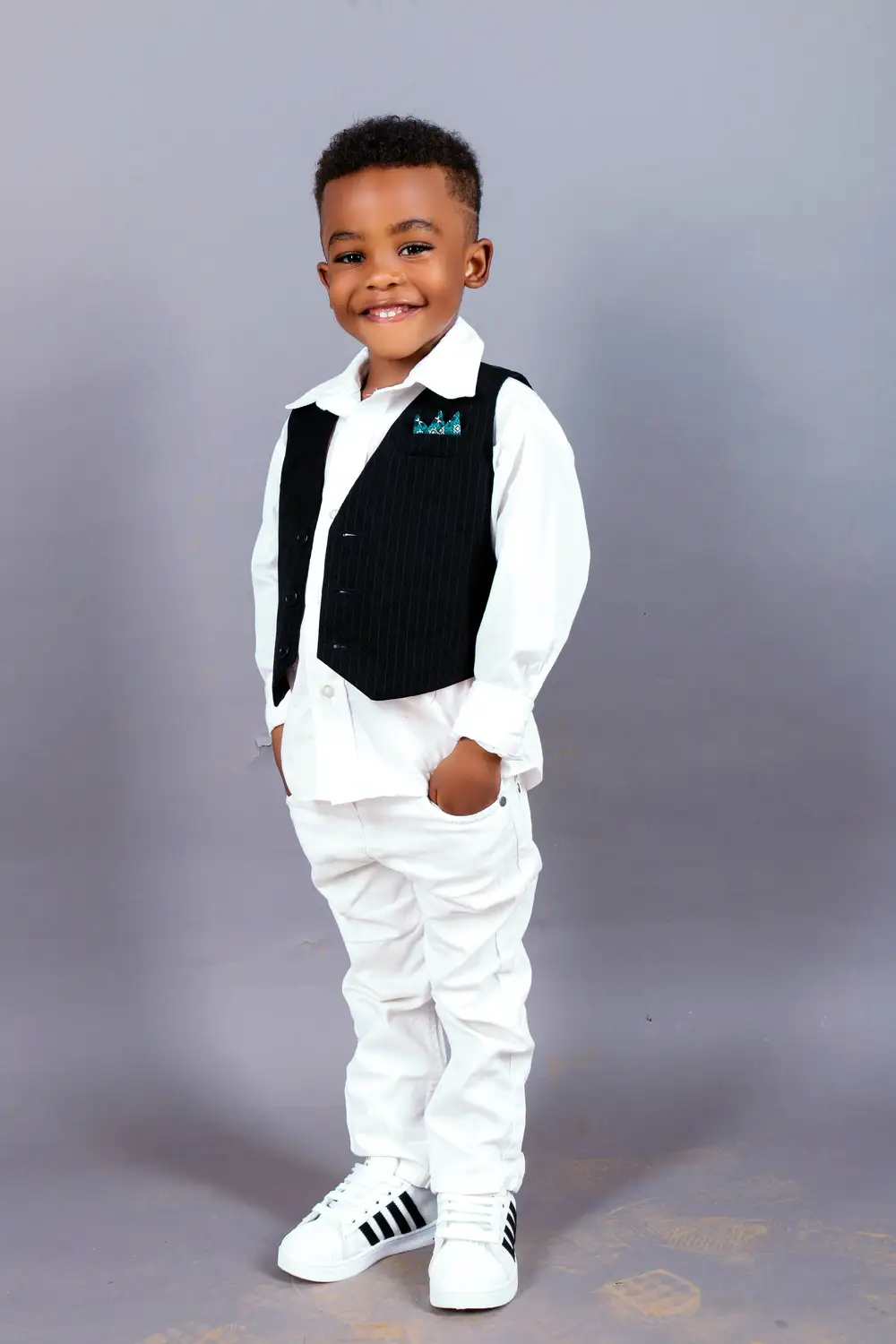 Child in a white outfit and black waist coat