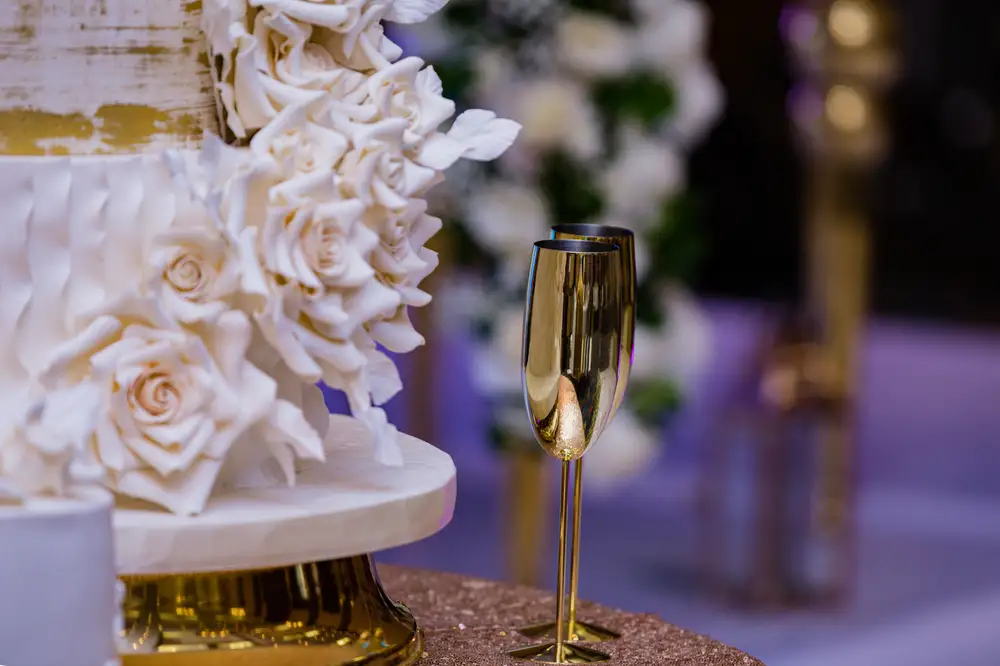 Reflective gold wine cups beside a White Cake