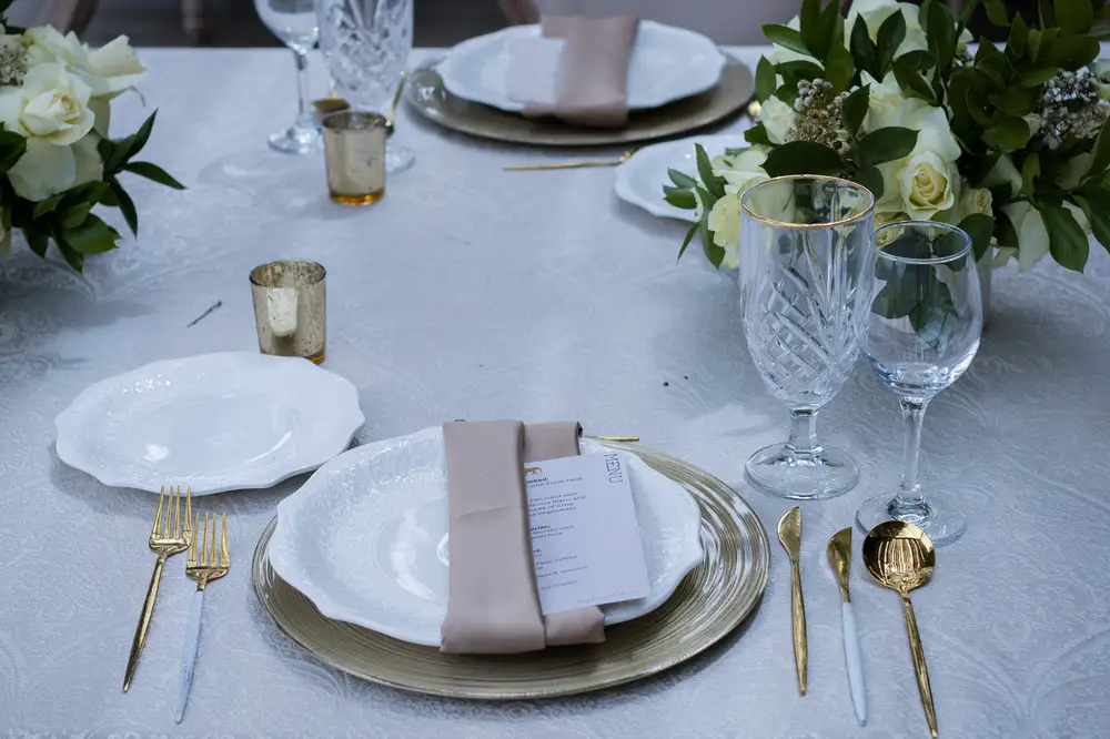 White Ceramic dishes with Golden cutlery and Wine glasses