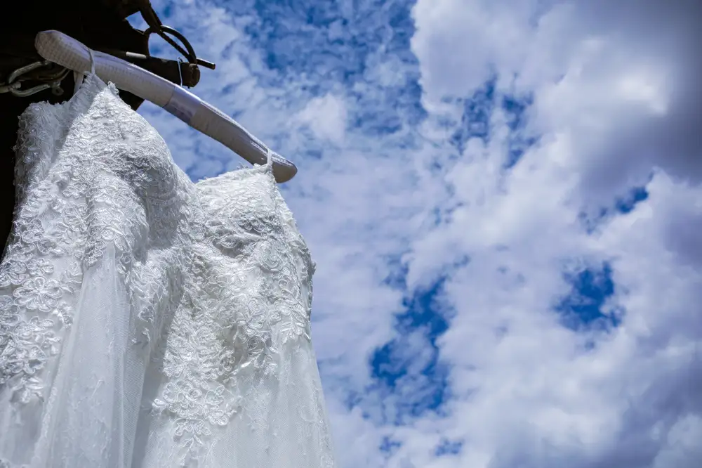 White wedding dress hung from a roof with a skyscape background