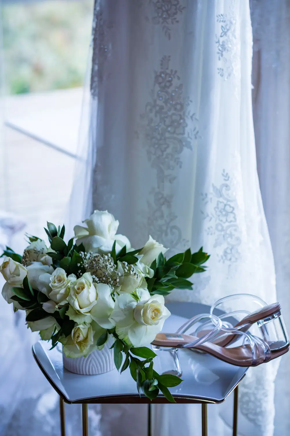 Closeup of White roses with a pair of glass shoes on a stool