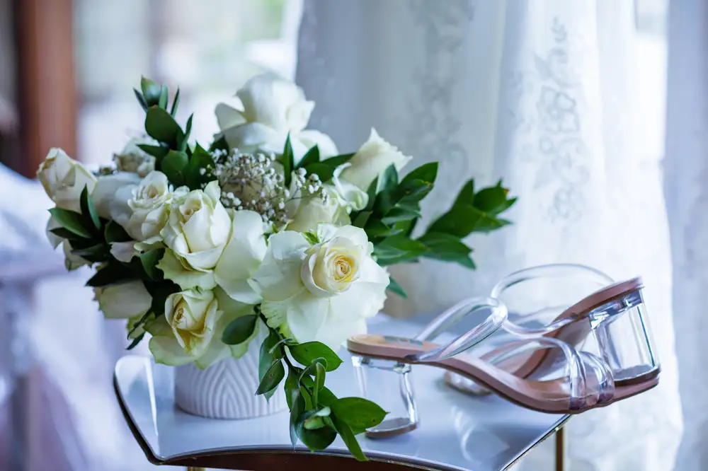 White roses with a pair of glass shoes on a table