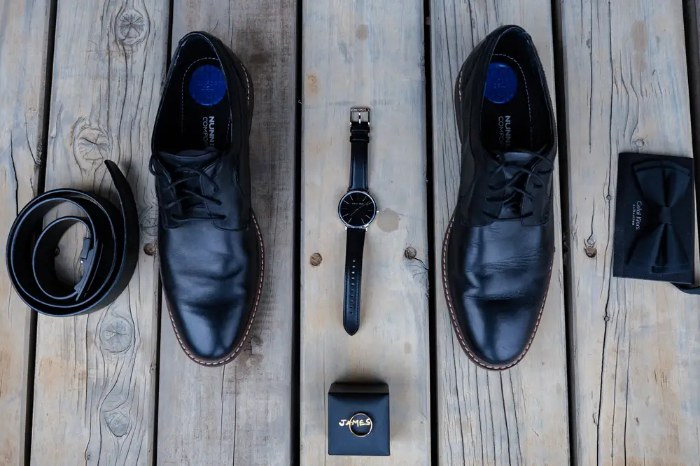 Black leather shoes with a wrist watch, belt and bowtie