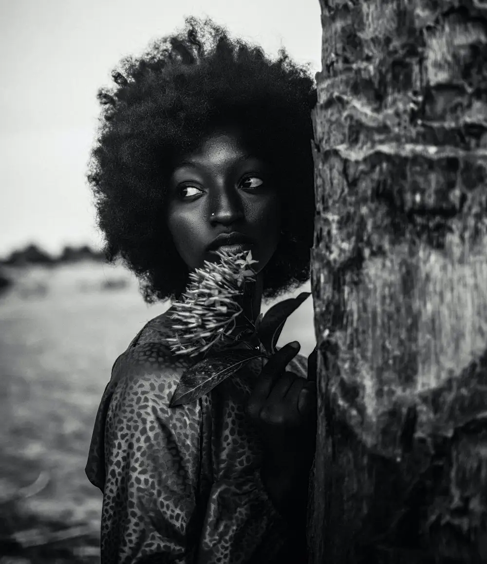 Afro lady leaning on a tree
