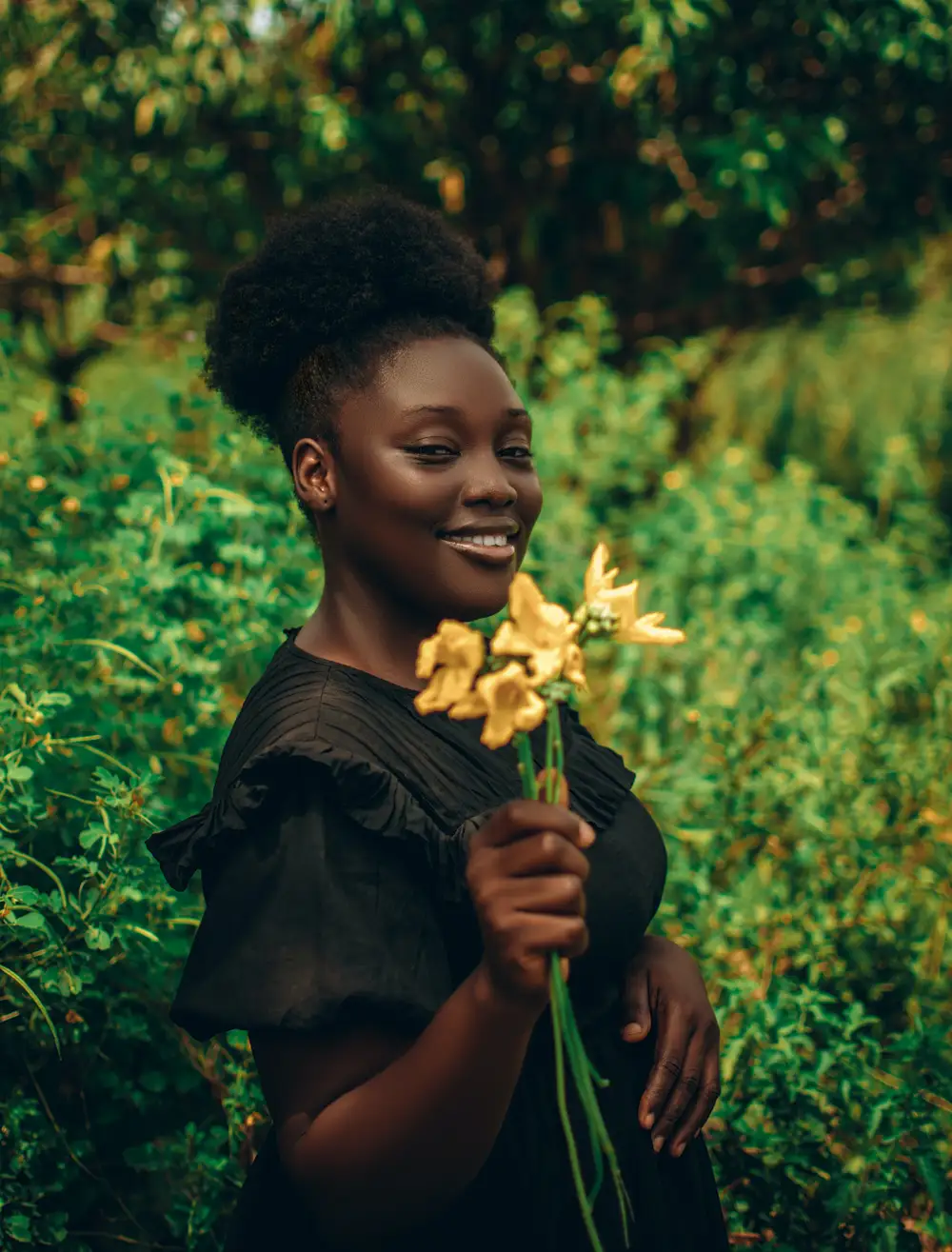 Lady on black gown smiling holding flower