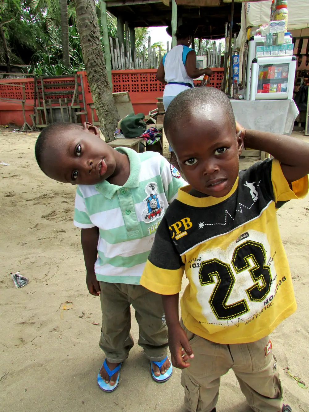 Two black children looking at the camera with a vendour behind them