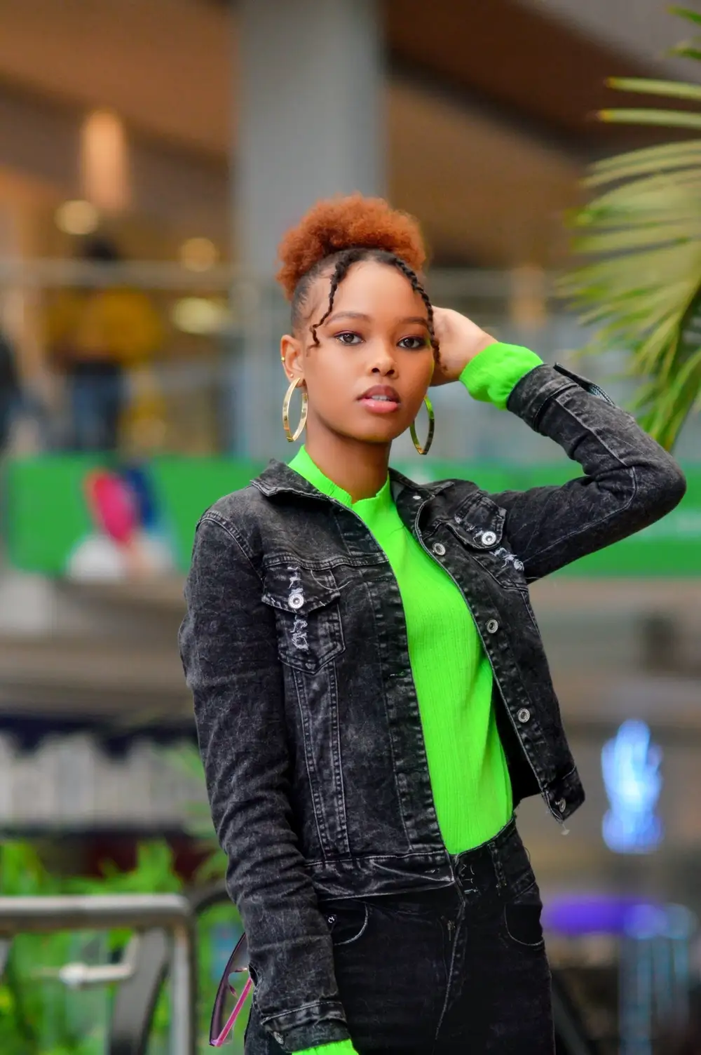 Woman poses in green shirt and denim jacket