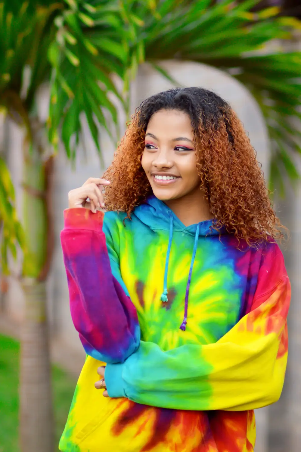 Woman smiling in a brightly coloured tie and dye hoodie