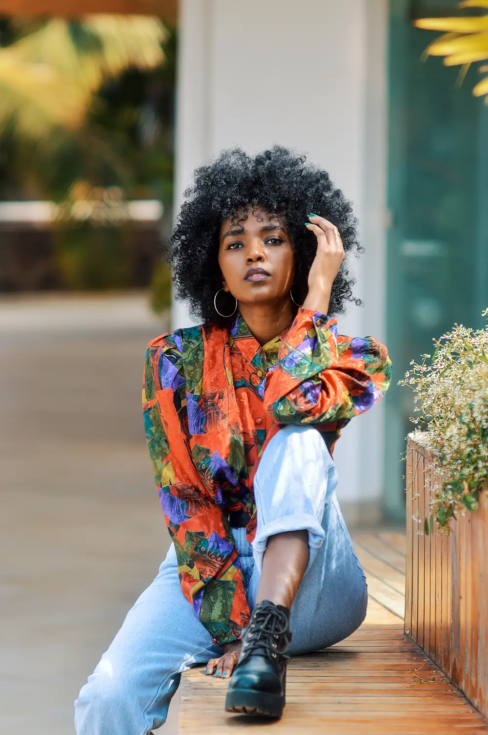 Lady with big hair in multicoloured shirt and boots.