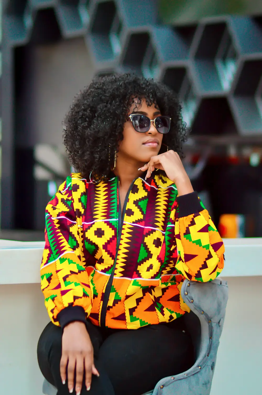 Woman wearing a kente patterned jacket.