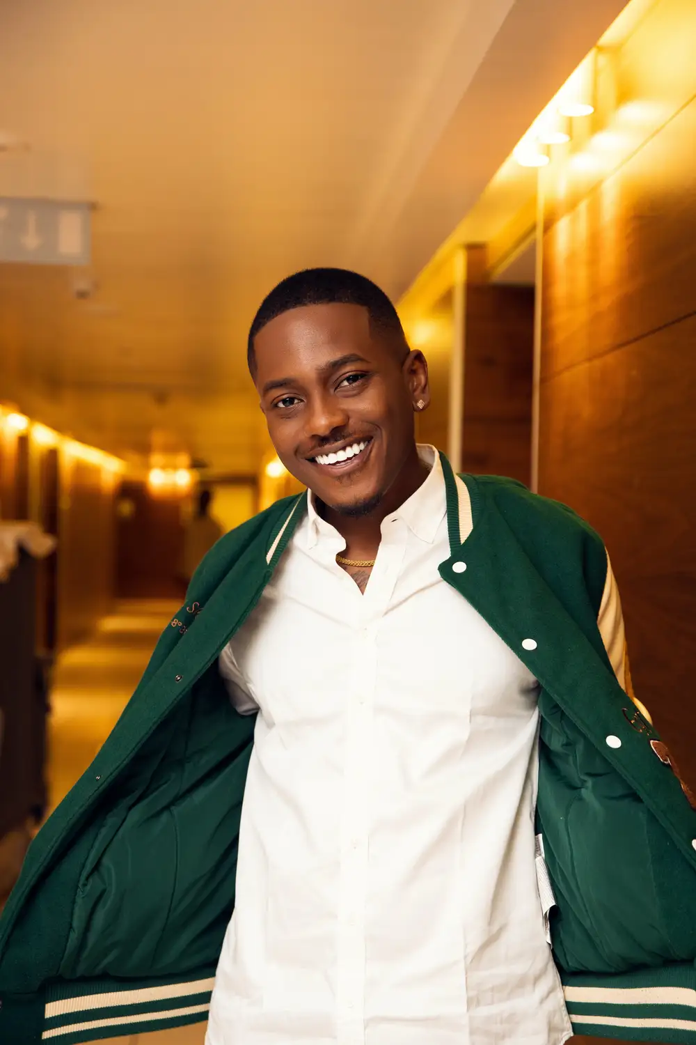 Man Wearing Green Jacket Standing at a Hallway