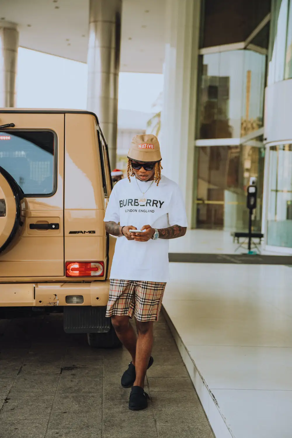 A Man in White Printed Shirt Walking Near Brown Vehicle