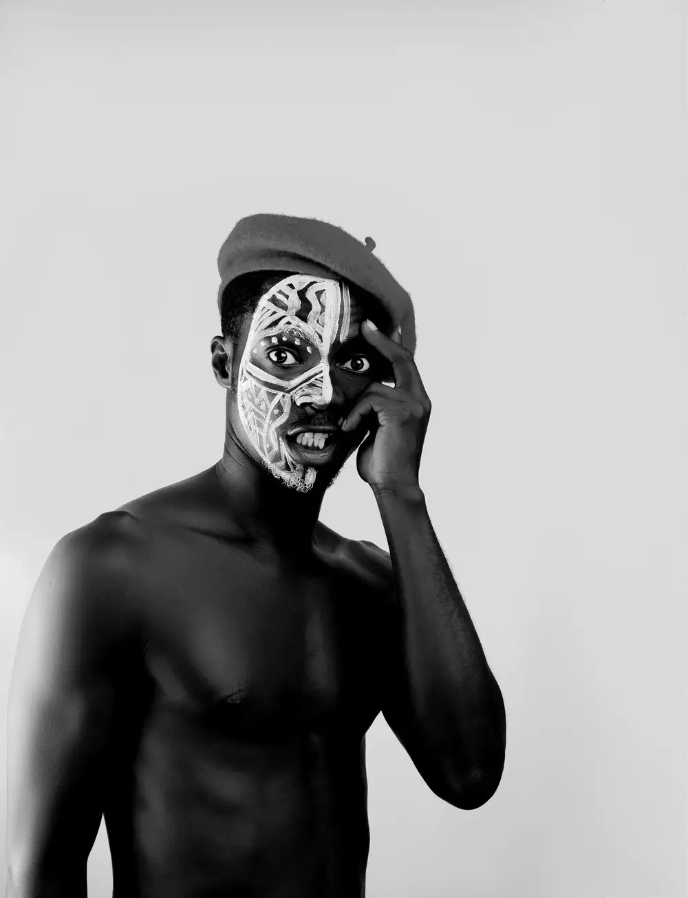 Man wearing beret with African skull face painting.