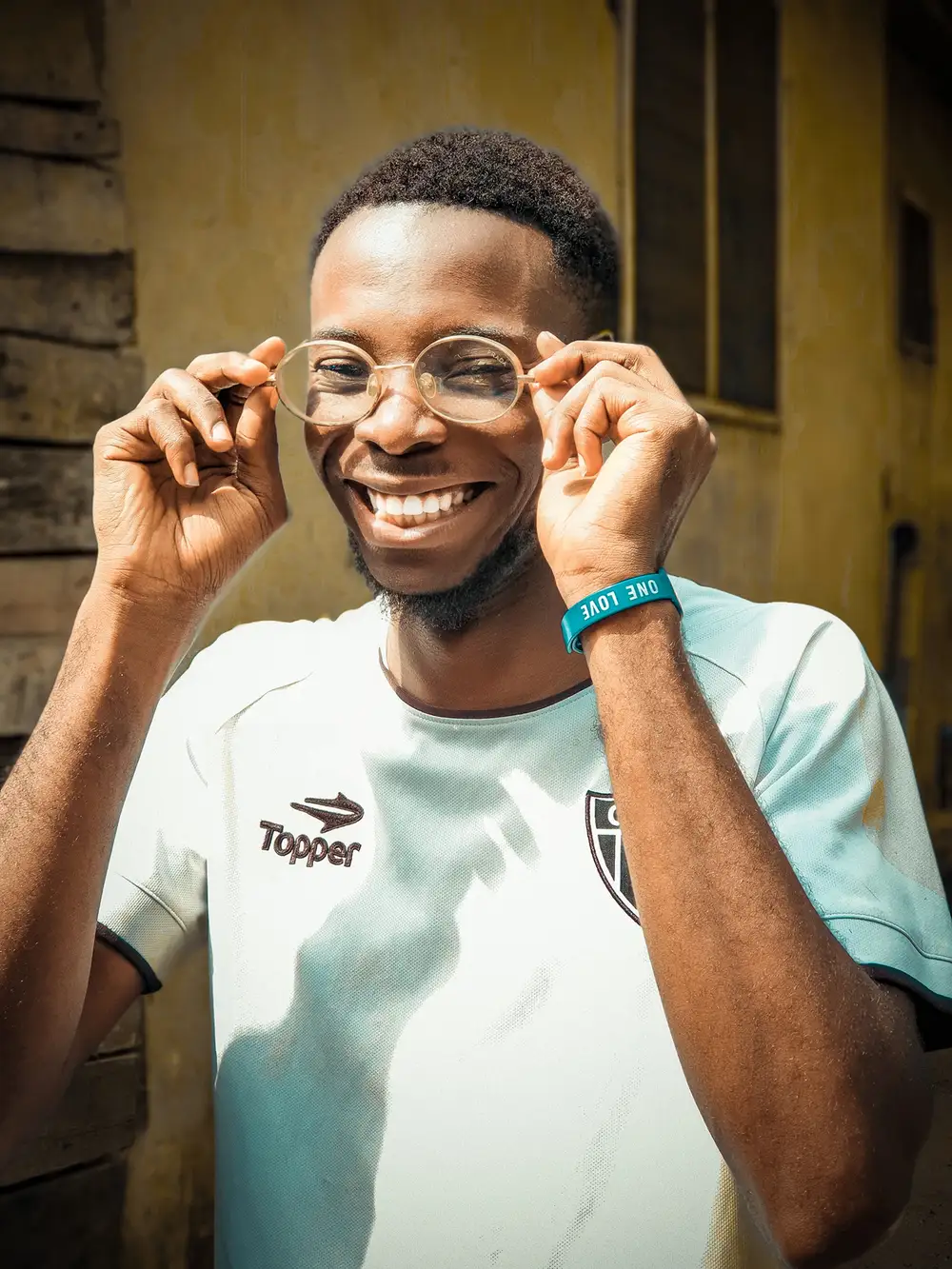 Young Man with a big grin holding his glasses
