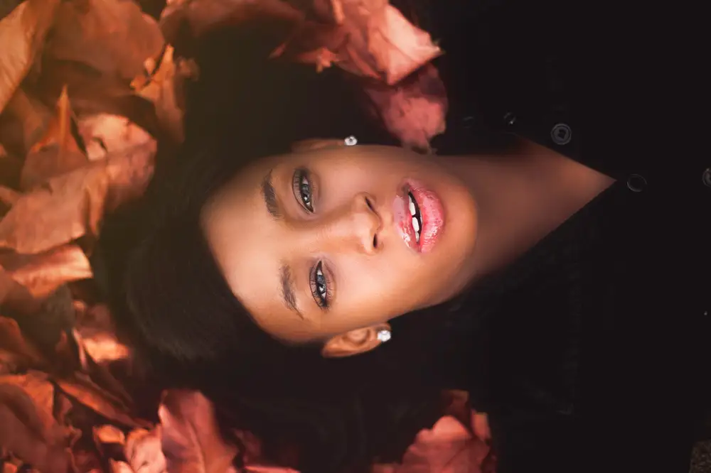 Face model laying down in red leaves
