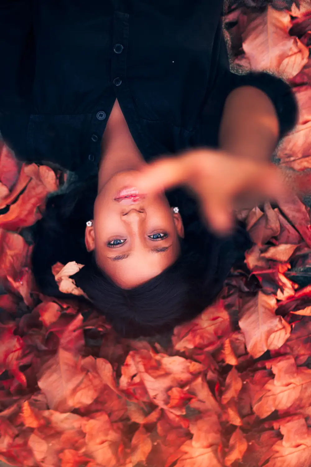 Face model laying down in red leaves