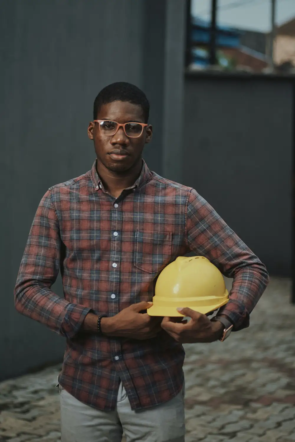 Portrait of a black man architect at a building site looking at camera. Confident civil engineering wearing a hardhat and eye goggles
