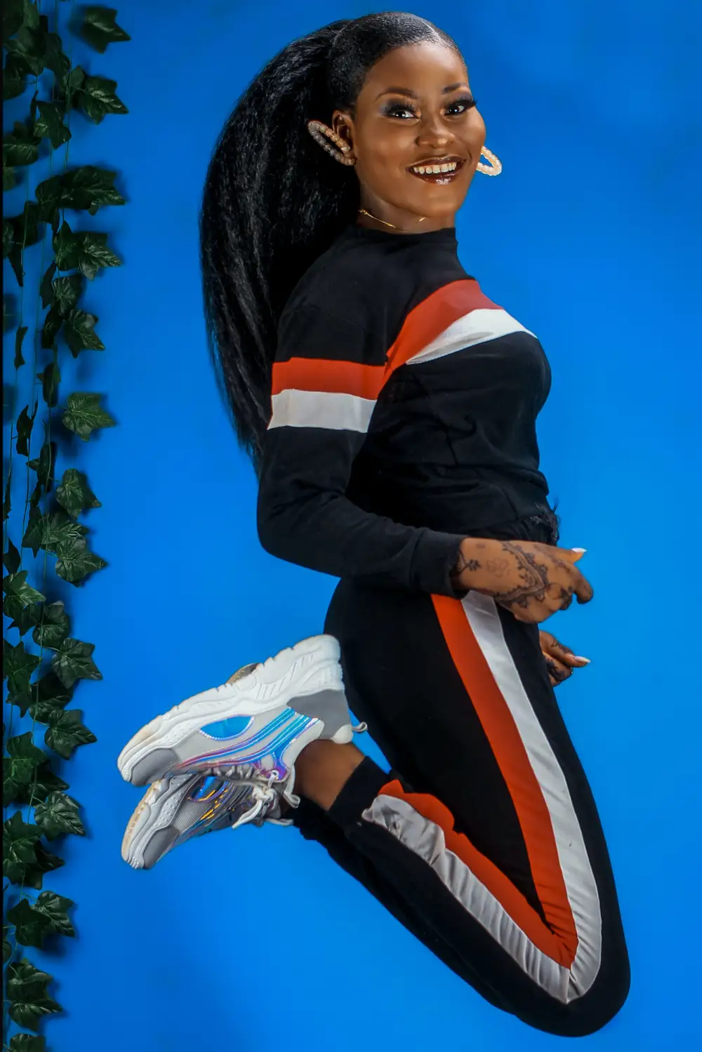 Woman in black and orange track suit sitting on a painted tyre