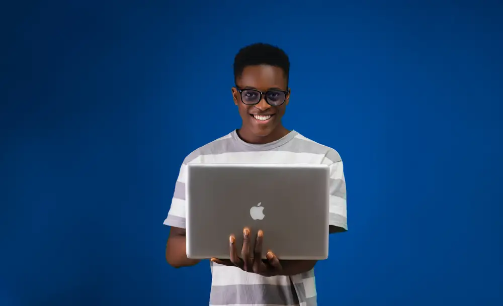 young man holding laptop and smiling