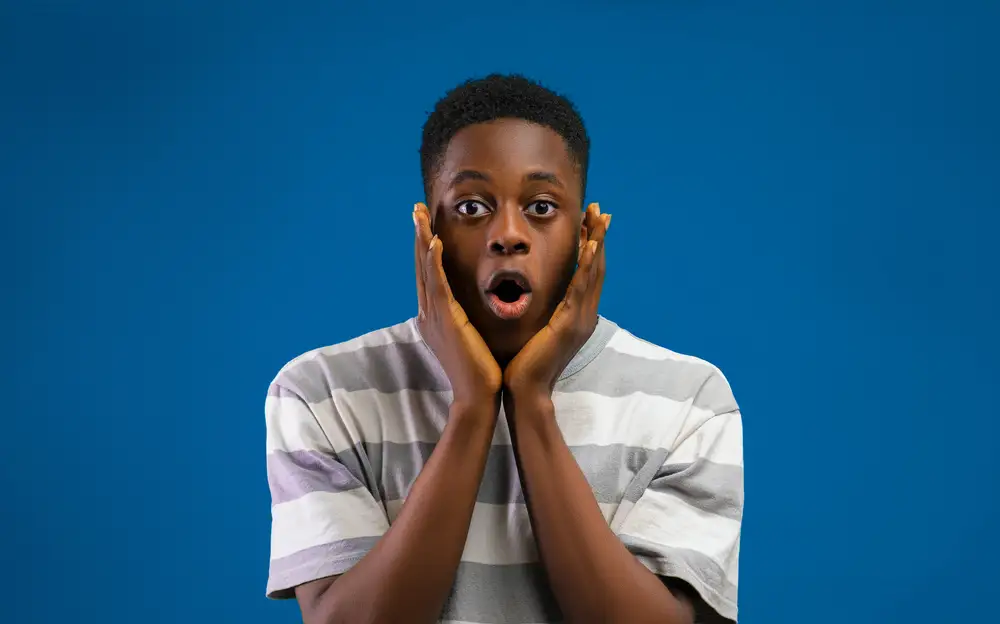 young man holding his face with shocked expression