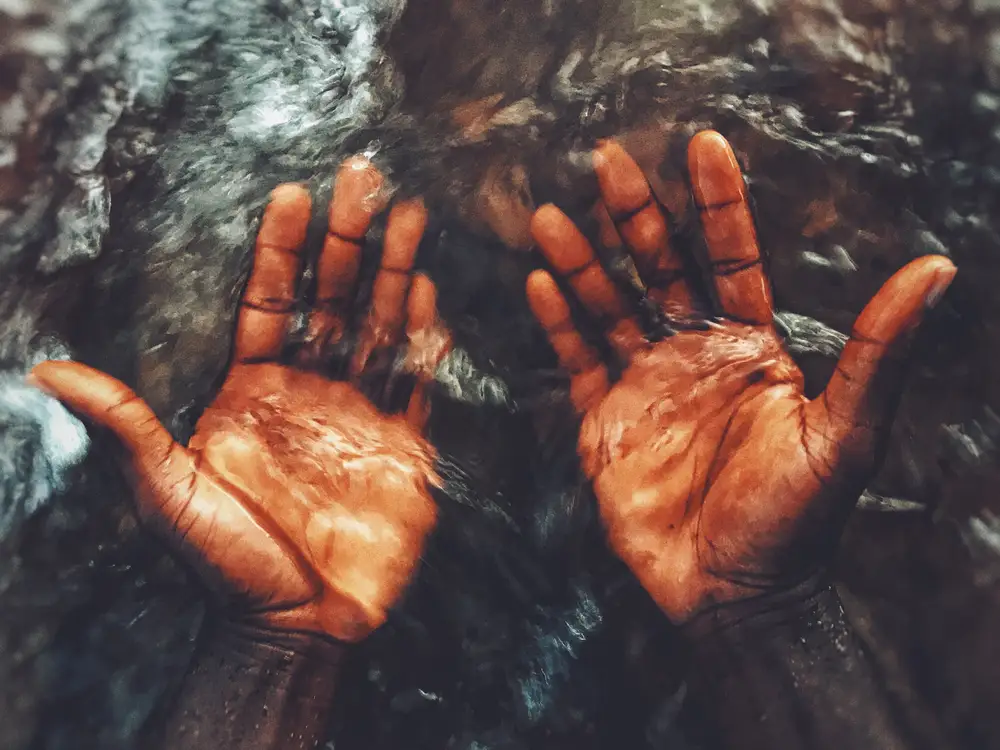 My brothers hands as water from a pond flows over them.