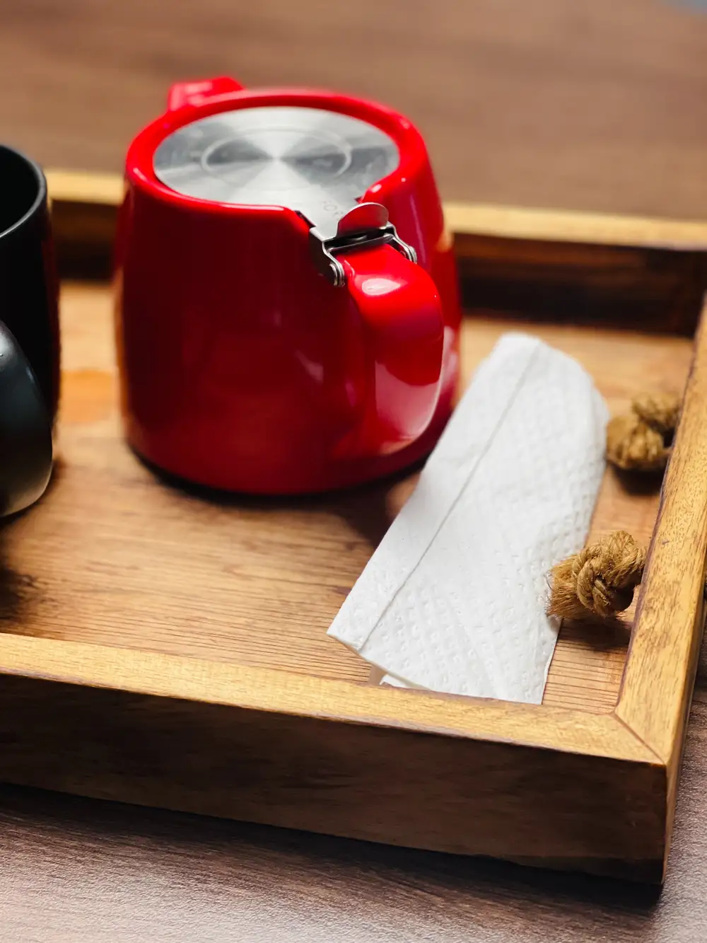 A red cup of tea on a wooden tray
