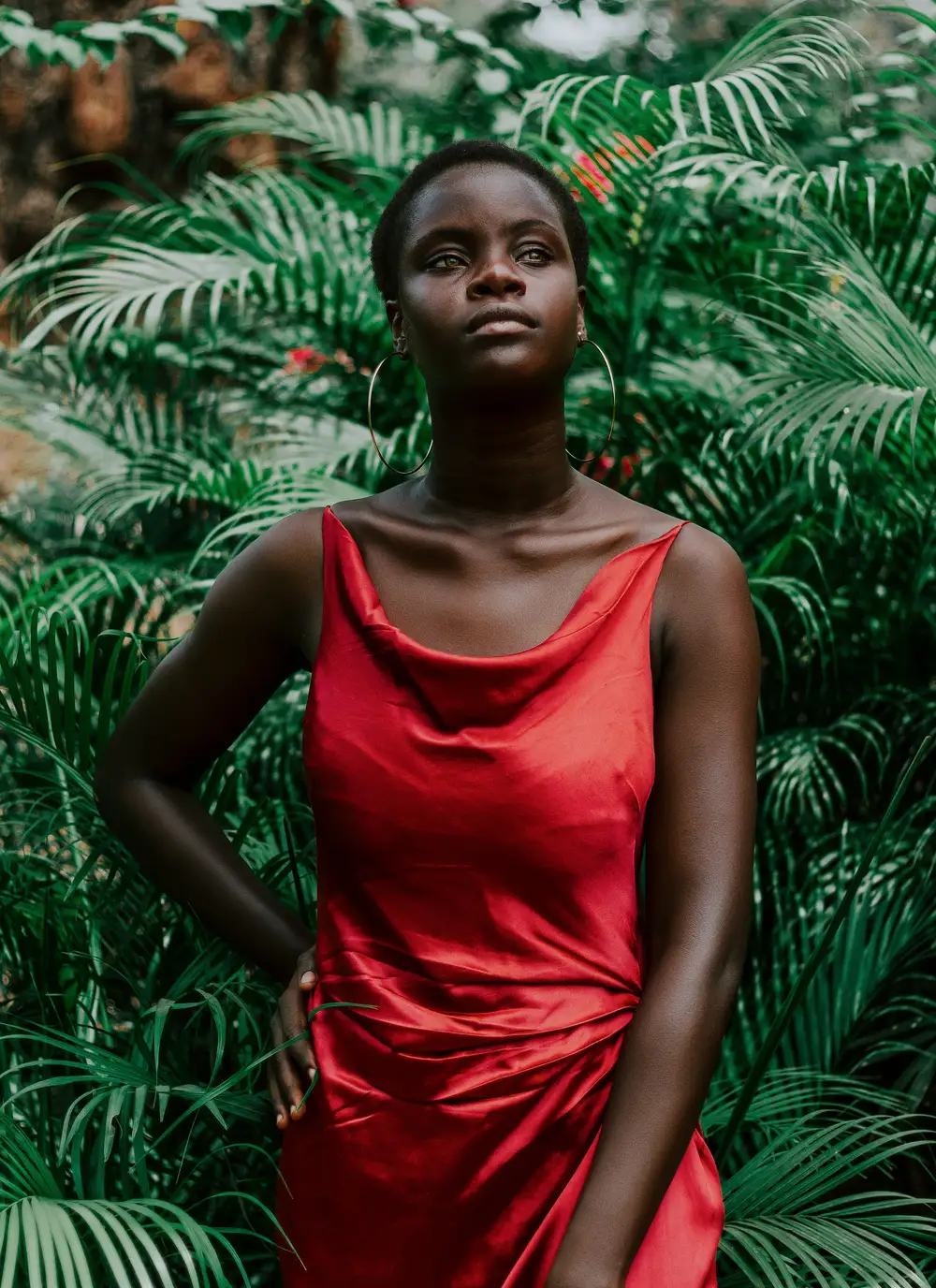 Beautiful black woman in a red dress posing in a garden