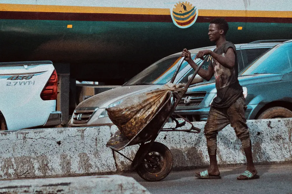 Alabaru (A Porter) rolling a wheel barrow in Lagos Market as a means of survival.