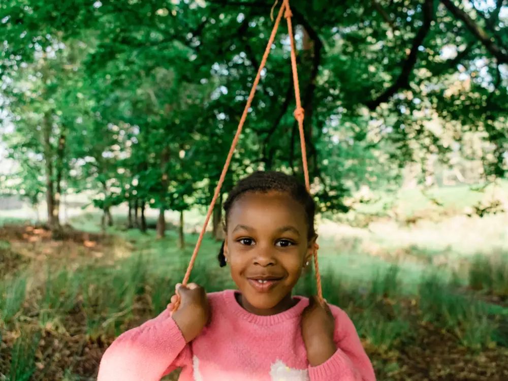 Little girl on a swing smiling.