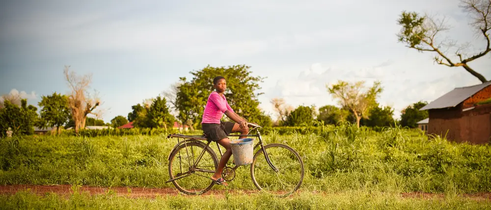 A girl rides her bicycle to the dam to fetch water.