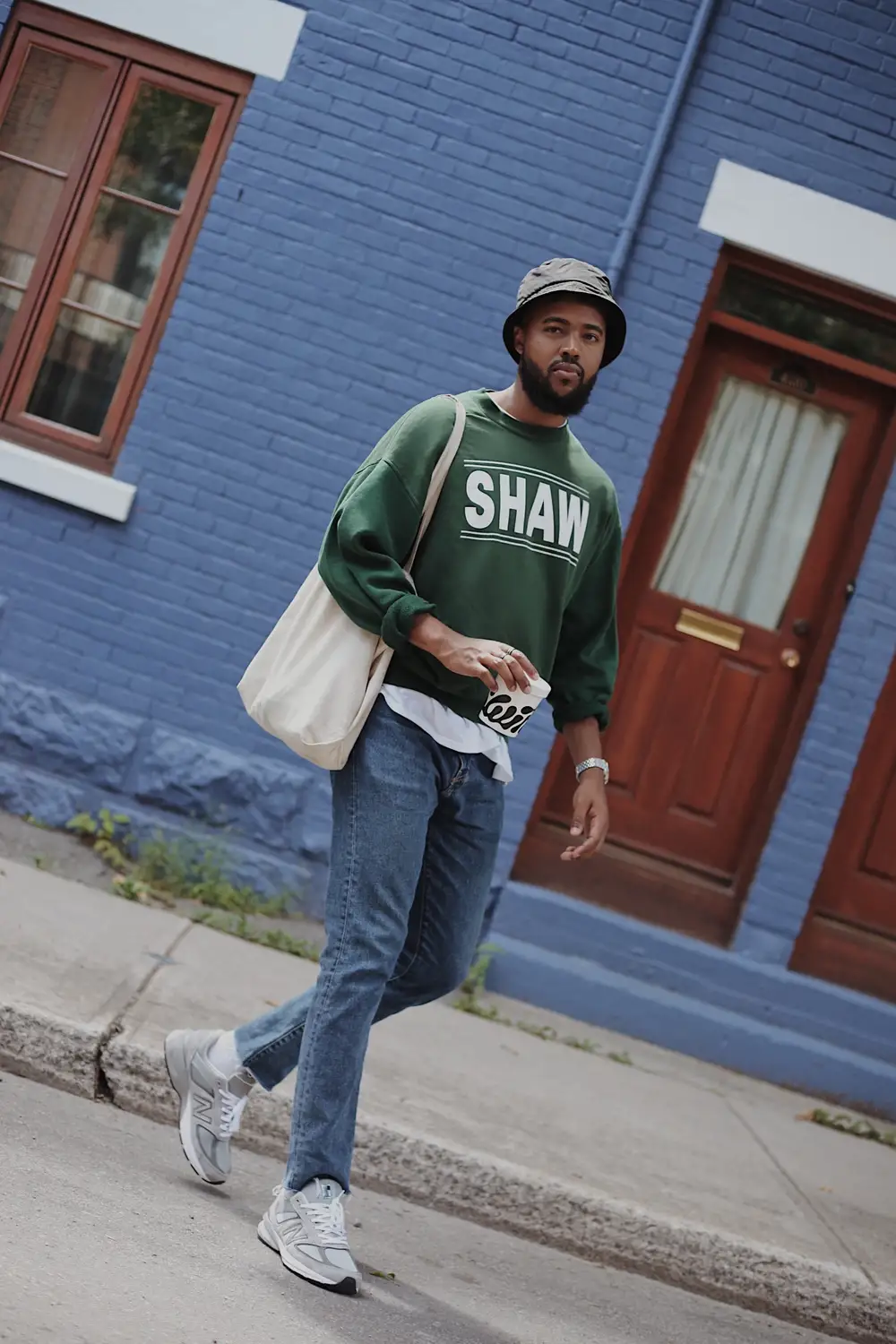 Man in green sweater carrying a tote bag