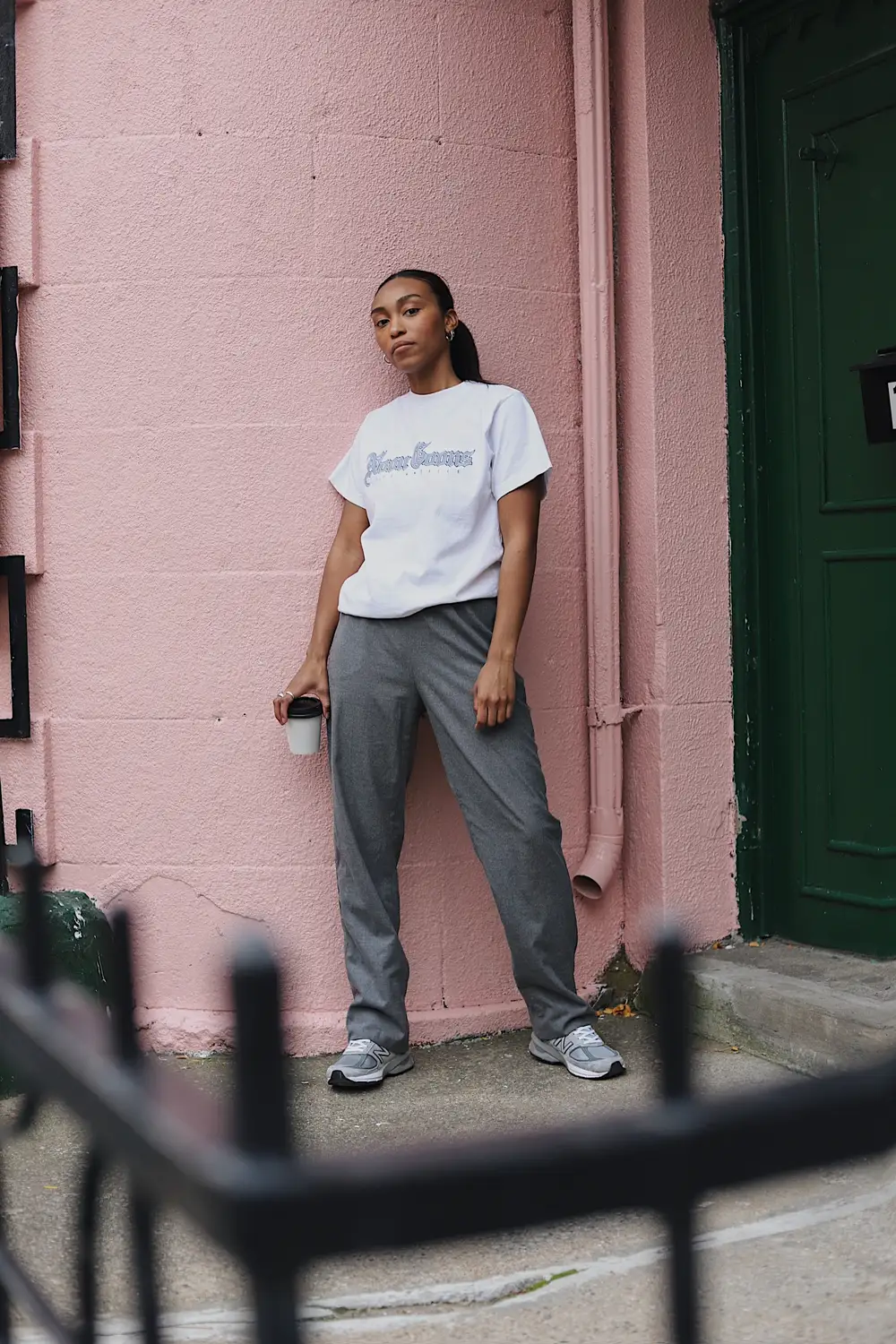 Woman in white t-shirt and grey sweatpants holding coffee cup